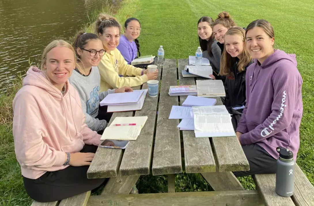 Students sitting at picnic table participating in Bible study